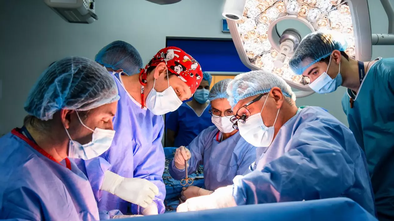 Medici chirurgi în sala de operație aplecați asupra pacientului