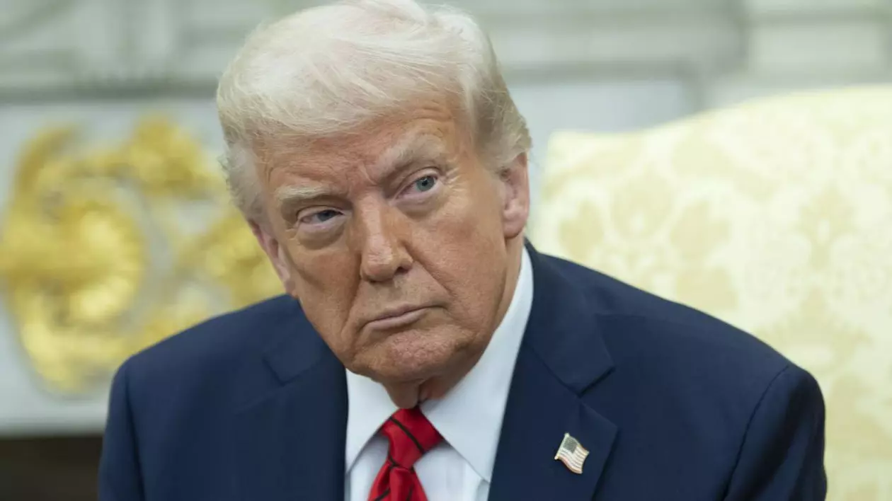 Donald Trump, în Biroul Oval, îmbrăcat într-un costum de culoare albastra cu o cravată roșie și insigna steagului american prinsă pe rever