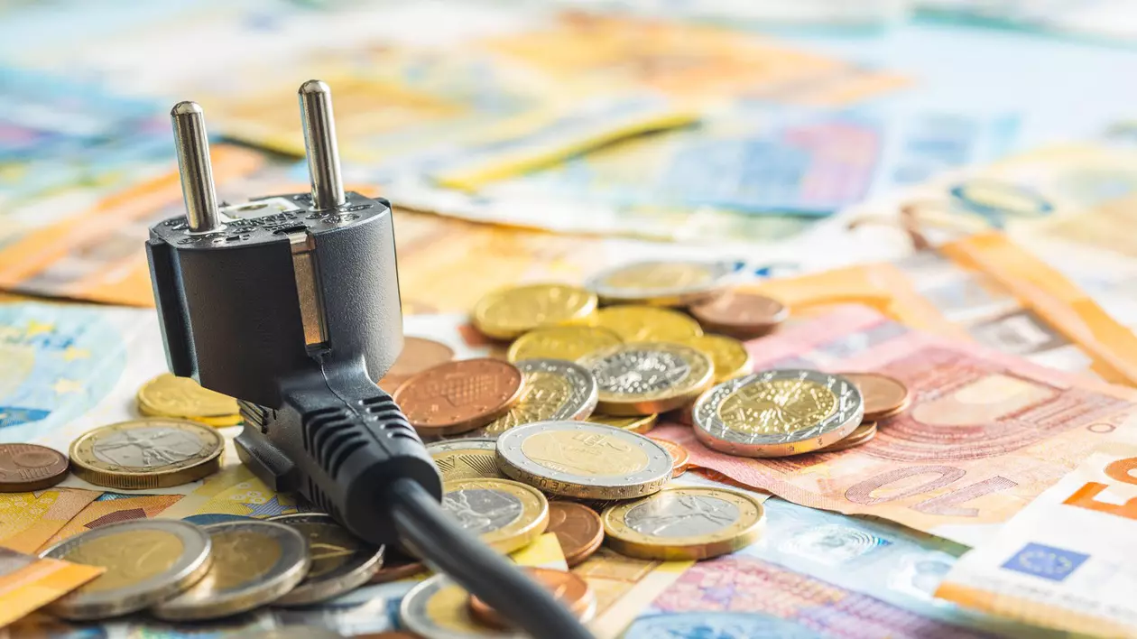 Ideea de scumpiri, bani imp[;tia'i pe o masă alături de un intrerupător electric