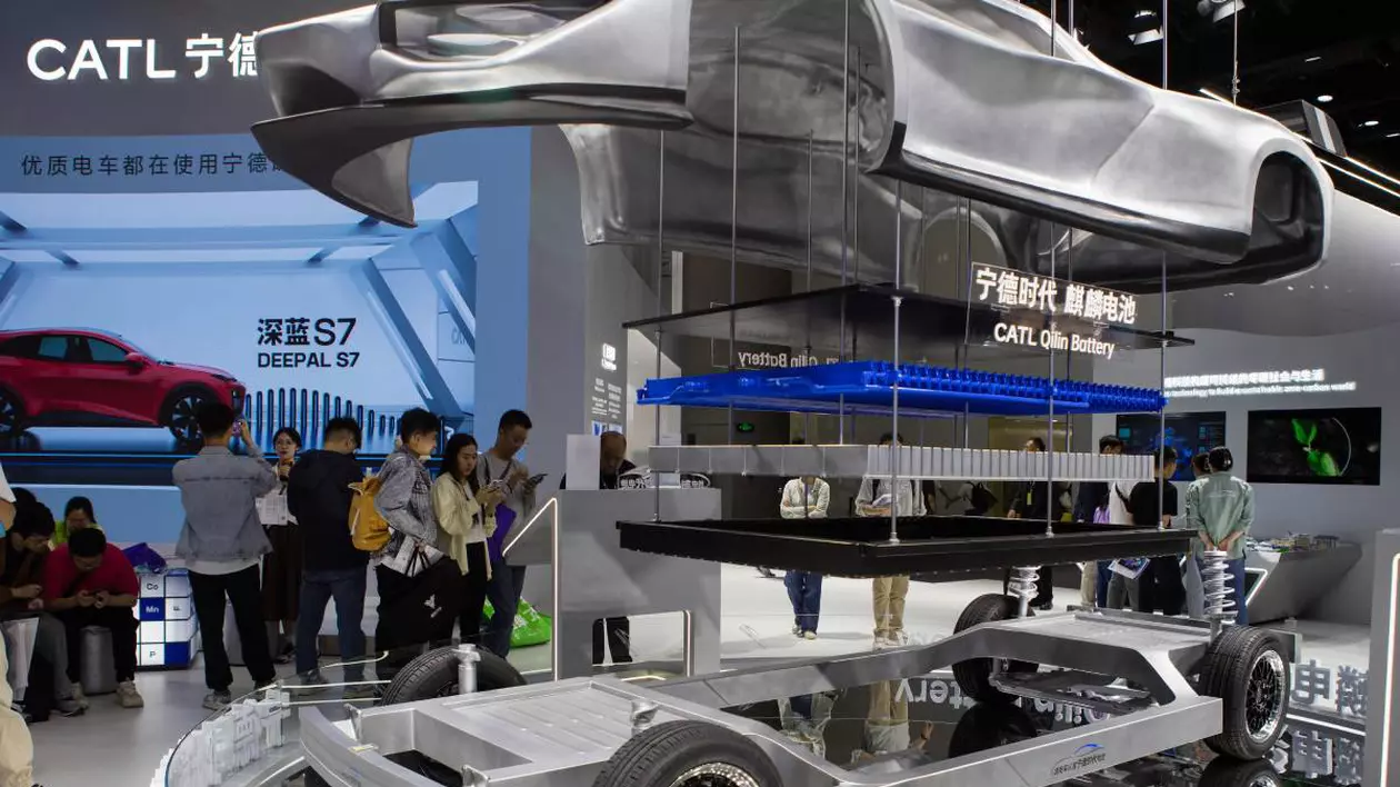 Stand de expoziție al companiei chineze CATL, lider mondial în producția de baterii pentru vehicule electrice. În prim-plan este prezentat un model demonstrativ al unui șasiu de mașină electrică. Pe fundal vizitatorii expoziției privesc panouri informative și reclame