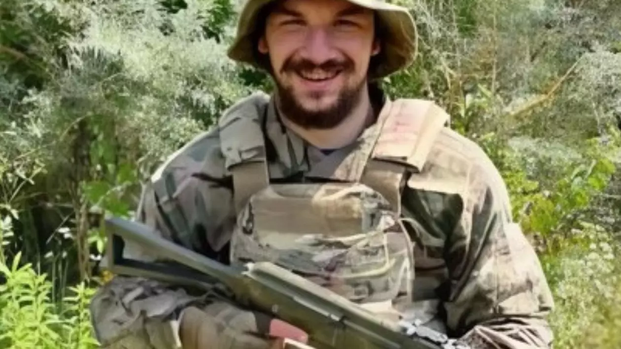 un tânăr din Ucraina ține o armă în mână și zâmbește