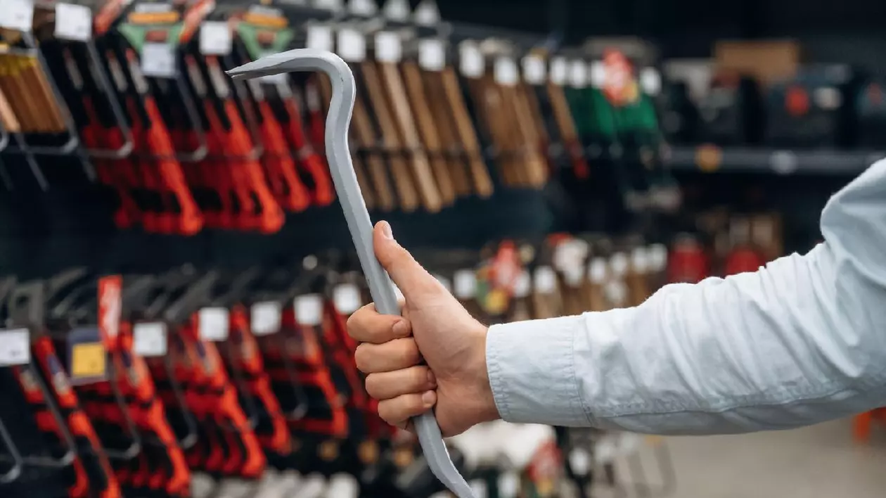 Un bărbat ține o rangă în mână, poartă o câmașă albă. Vedere detaliată de aproape a mâinii omului în magazinul de unelte