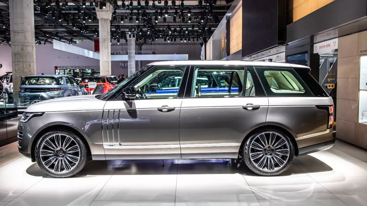 Mașină model Range Rover, expus într-un salon auto. SUV-ul, de culoare gri metalizat, este fotografiat din profil