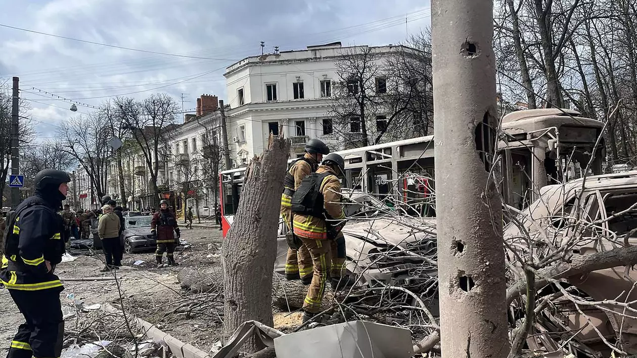 Trei salvatori ucraineni surprinși pe o stradă din Sumî, după atacul Rusiei. În imagini pot fi văzuți copaci la pământ și mașini distruse