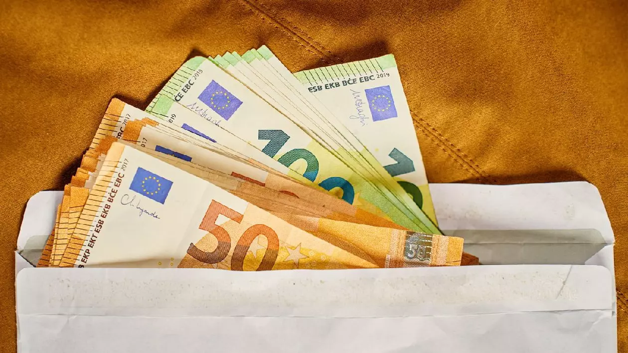 Bancnote euro în plic alb, vedere de sus. Close up de bani cash pe fundal maro. Concept de corupție, mită și plăți ascunse în numerar