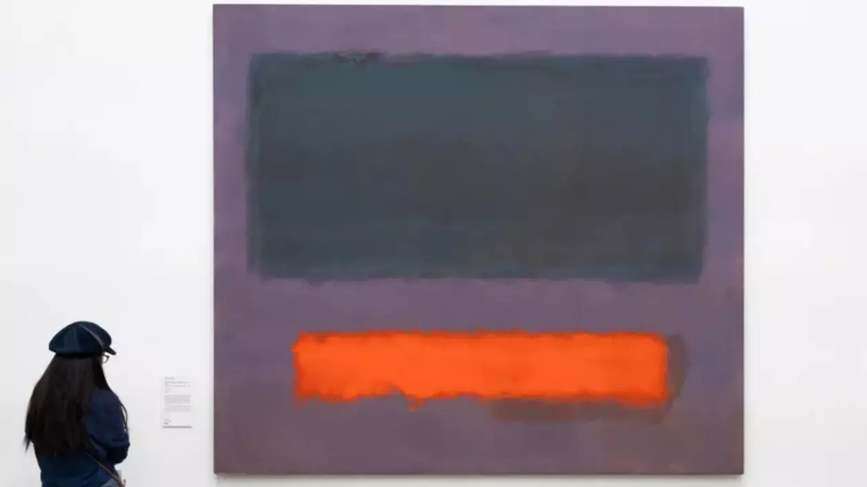 O tânără fotografiată cu spatele privește tabloul „Grey, Orange on Maroon, No. 8”, pictat de Mark Rothko în 1960, și expus la muzeul din Olanda