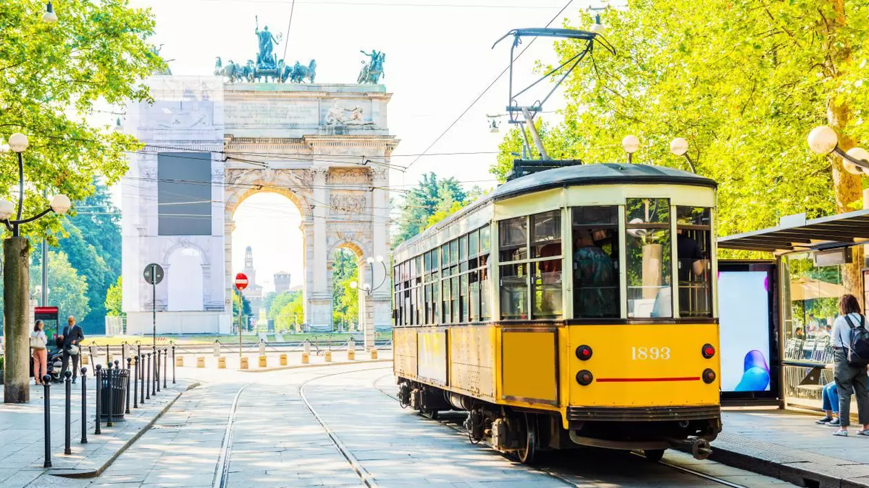 Vedere de la Arcul Păcii (Arco della Pace) din Milano, Italia, iar în prim-plan este un tramvai galben care a ajuns în stație