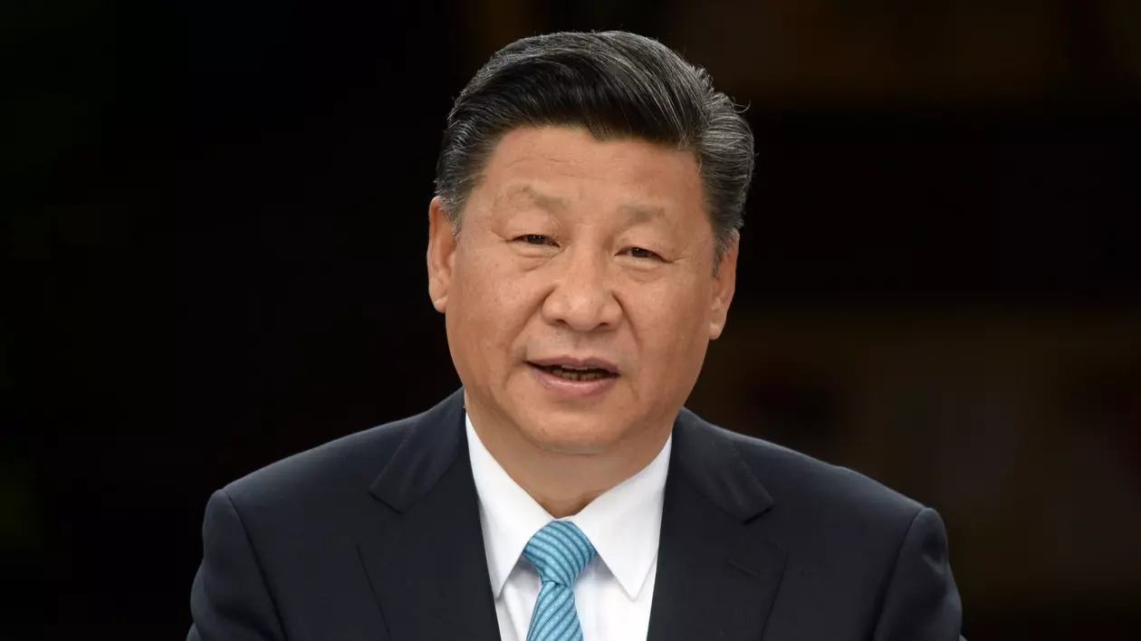 Poză cu Xi Jinping - poartă o cămașă albă, cu o cravată turcoaz cu dungi albe și un sacou negru.