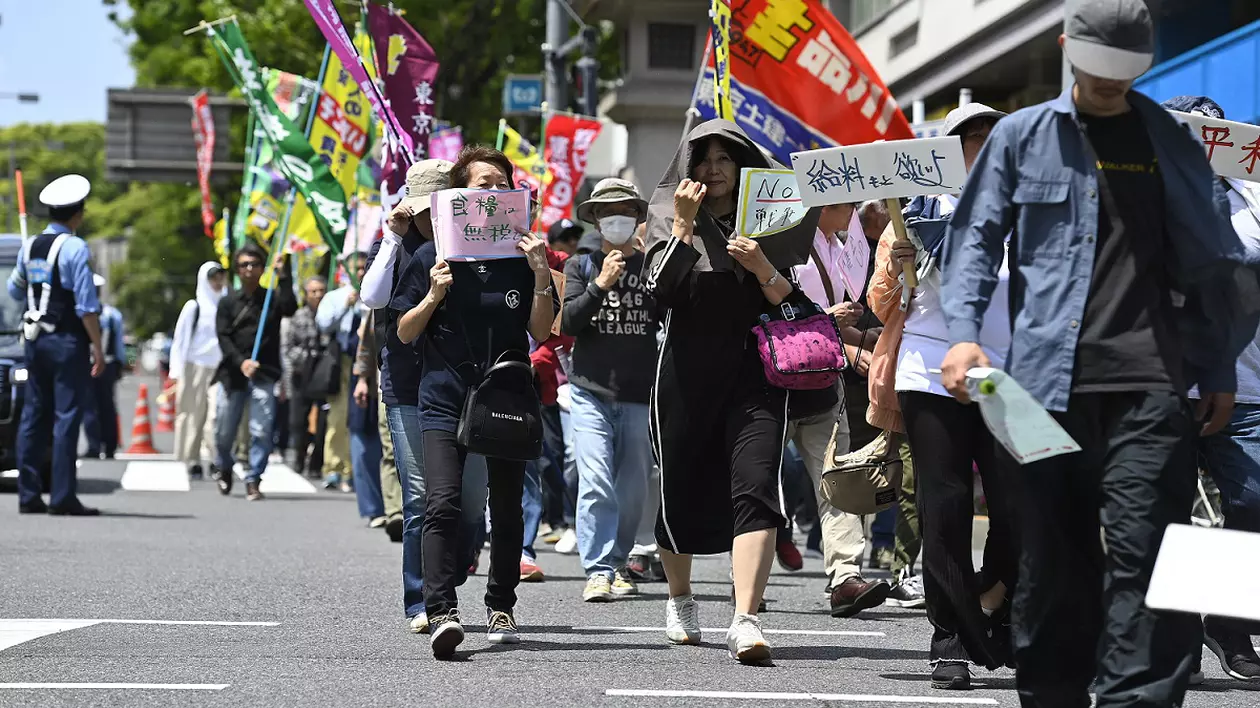 Ținând în mâini pancarte și scandând, oamenii mărșăluiesc de 1 Mai, în Japonia