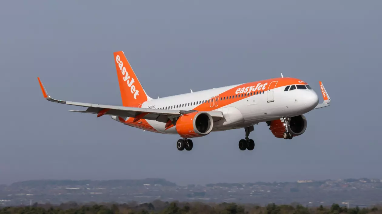 În imagine este ilustrat un avion Easy Jet alb cu portocaliu, aflat în timpul zborului
