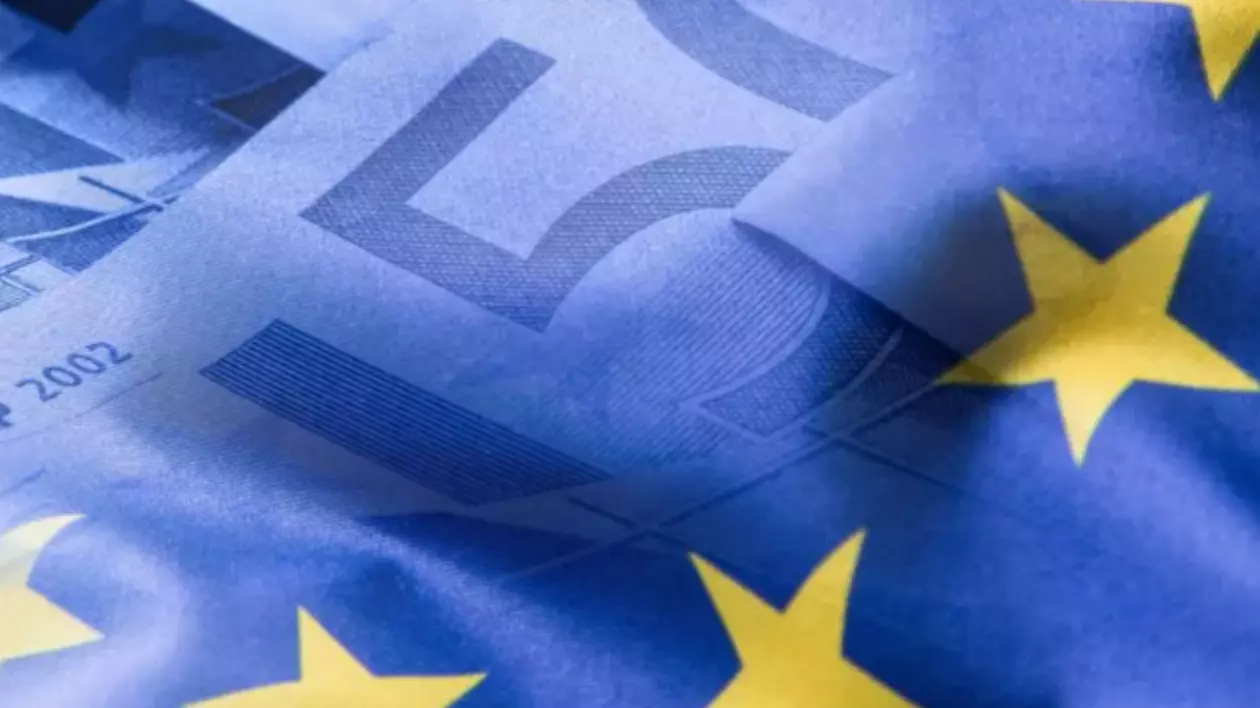 Imaginea prezintă o suprapunere simbolică între două elemente vizuale reprezentative ale Uniunii Europene: bancnote euro și steagul Uniunii Europene.