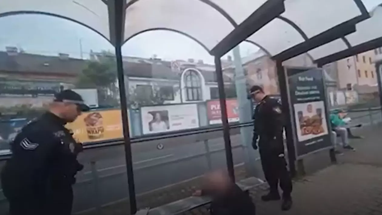 În imagine este ilustrat un bărbat care se află sub o bancă. Lângă acesta se află doi polițiști