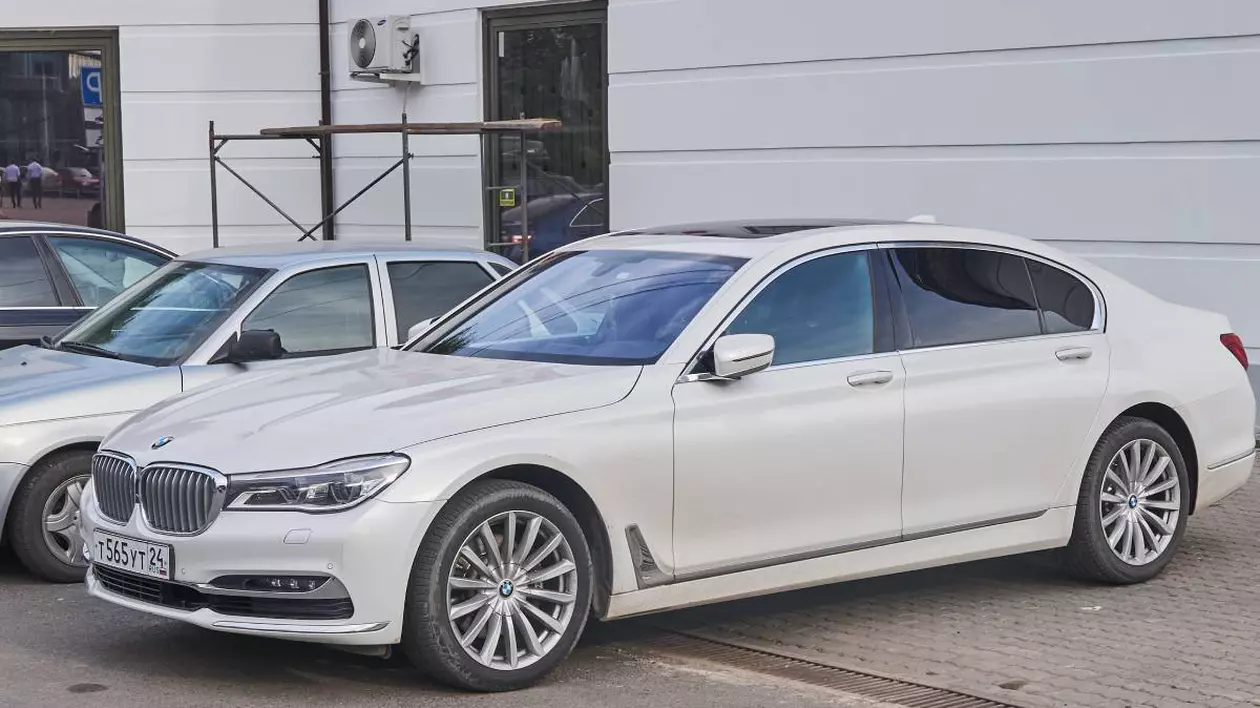 Un BMW Seria 7 alb, di 2017, în timp ce stă cu oglinzile închise într-o parcare din Germania.
