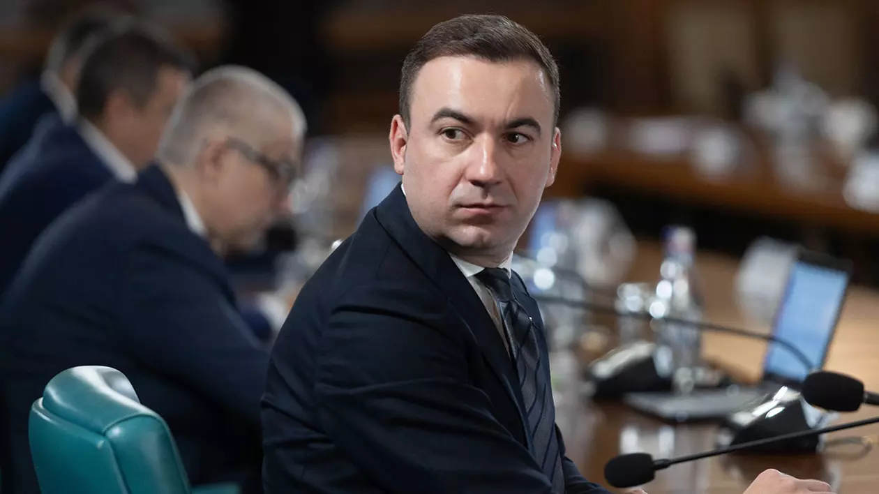 Bogdan Ivan, ministrul Investițiilor și Proiectelor Europene, participă la o ședință de guvern, este întors la masă și privește în spate