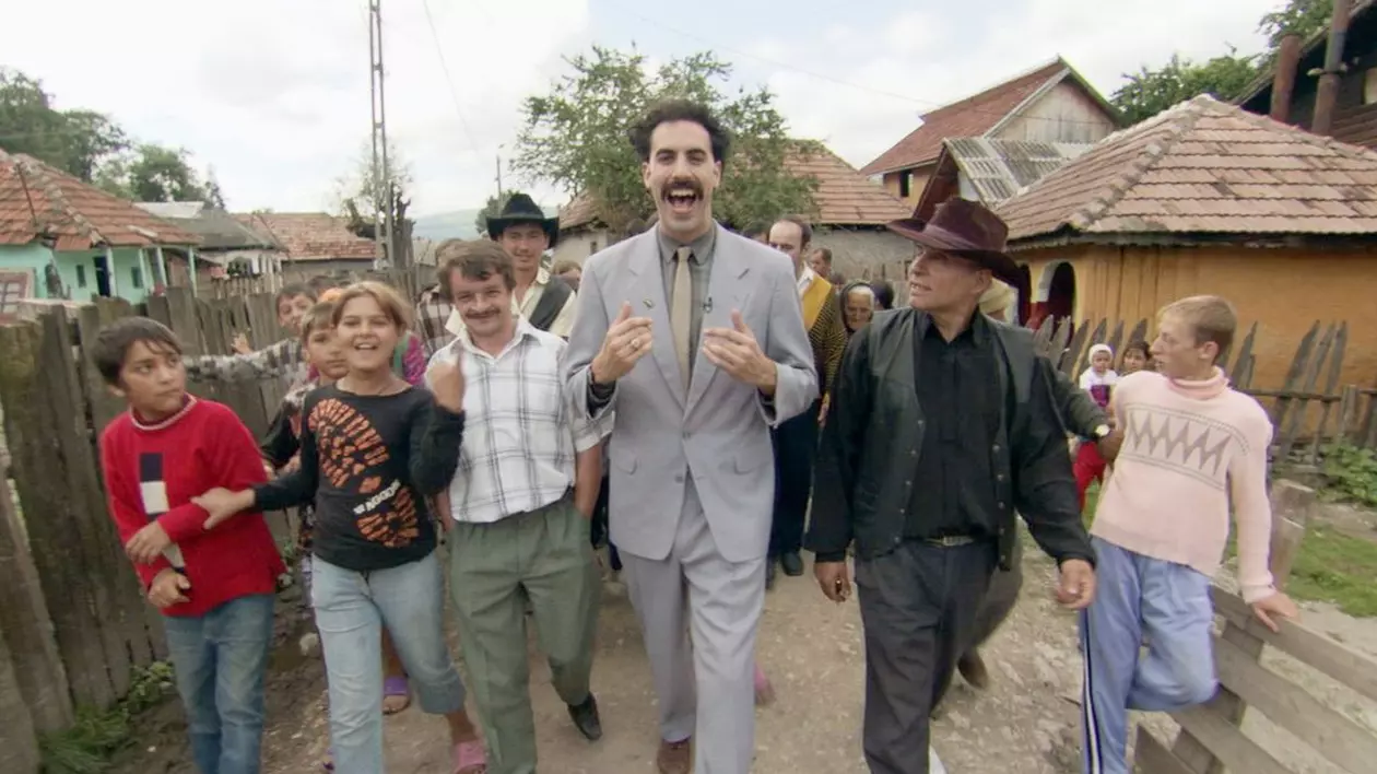 Cadru din filmul „Borat Cultural Learnings of America for Make Benefit Glorious Nation of Kazakhstan”, cu actorul Sacha Baron Cohen, mergând pe stradă, înconjurat de cetățenii din Glod