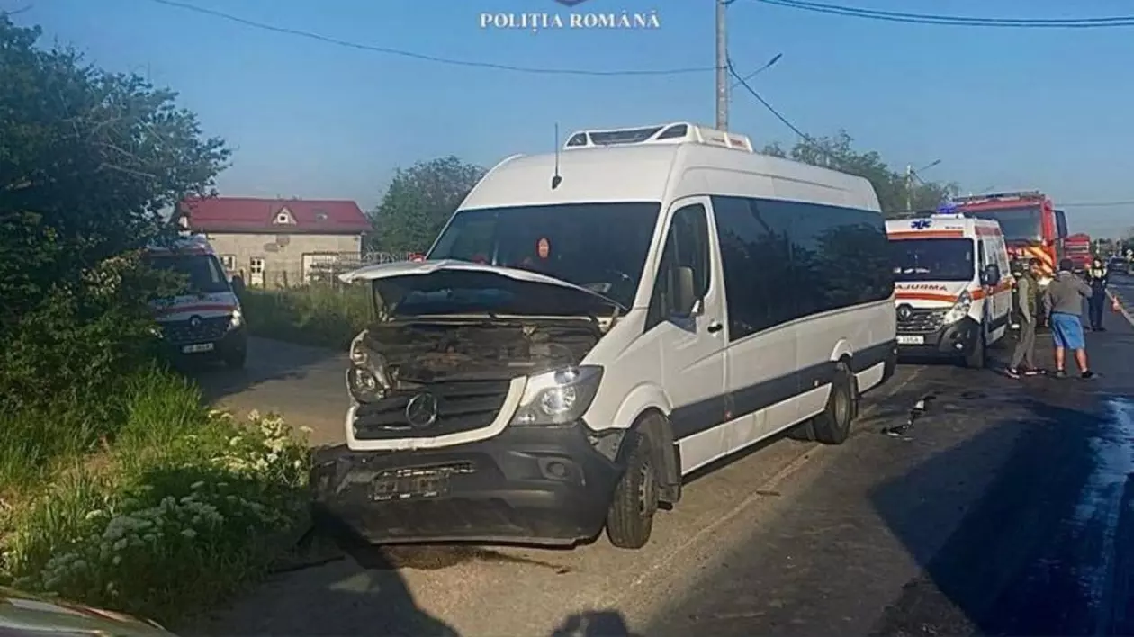 Un microbuz avariat în accident, pe o șosea. În spate sunt ambulaanțe și mașini de pompieri