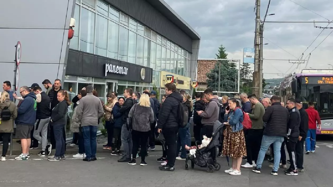 mai mulți oameni stau la coadă în fața unui centru comercial din Cluj
