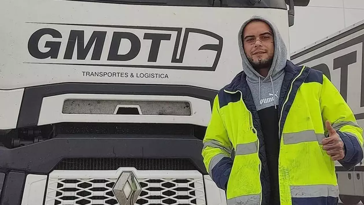 Cristian Stratan, îmbrăcat cu o geacă de lucru, de culoare verde, în fața unui camion de culoare albă