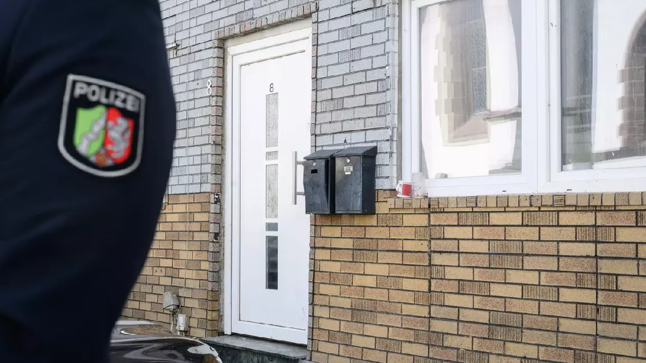 Un ofițer de poliție stă în fața unei case sigilate.
