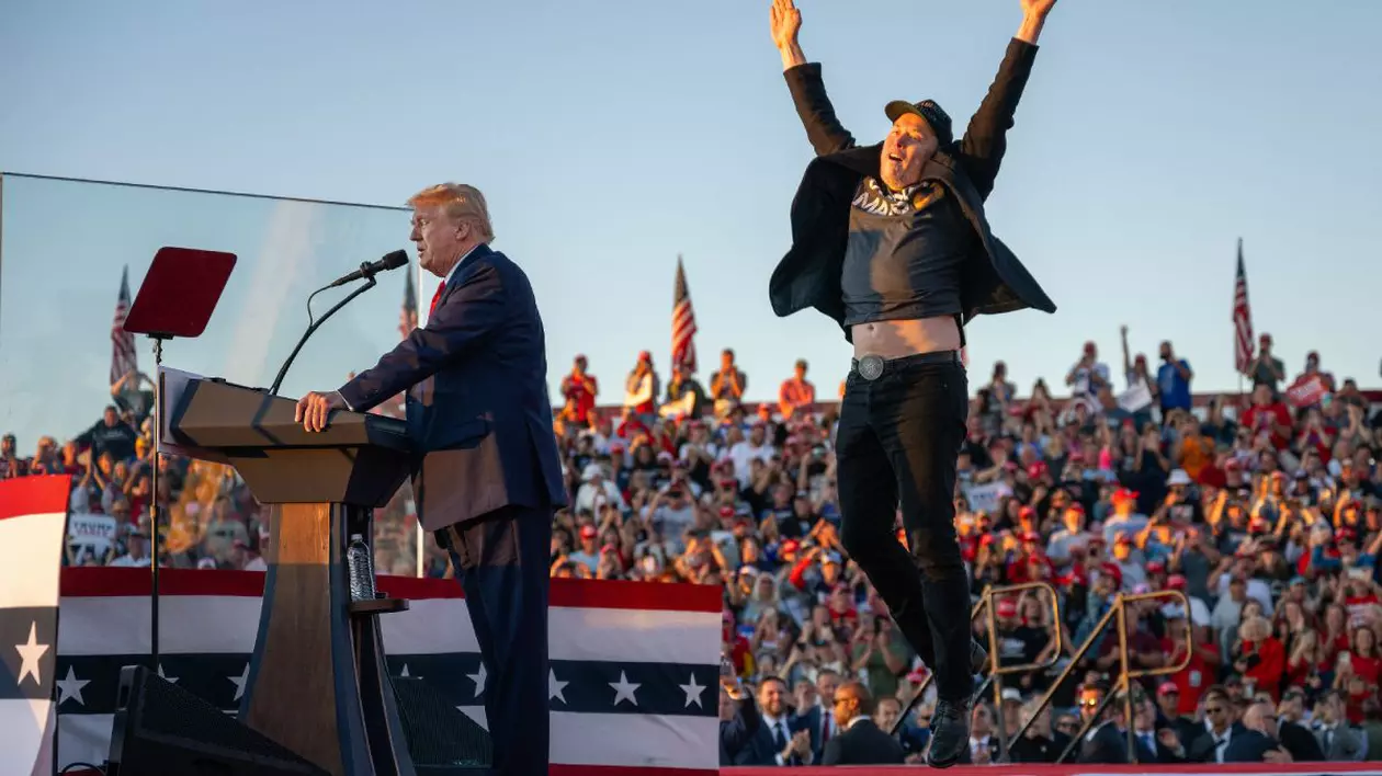 Donald Trump, pe o scenă, în timpul campaniei electorale, îmbrăcat în costum, iar alături de el, Elon Musk, îmbrăcat cu blugi, tricou și sacou, în timp ce sare în sus, cu mâinile îndreptate spre cer