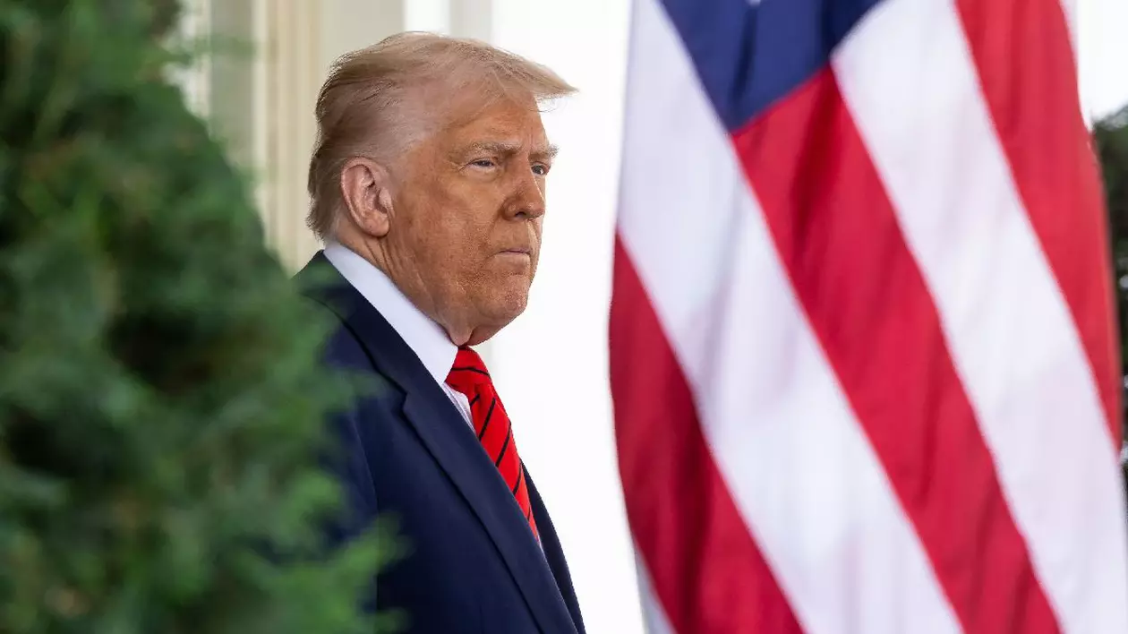Donald Trump privește în zare lângă un steag al Statelor Unite