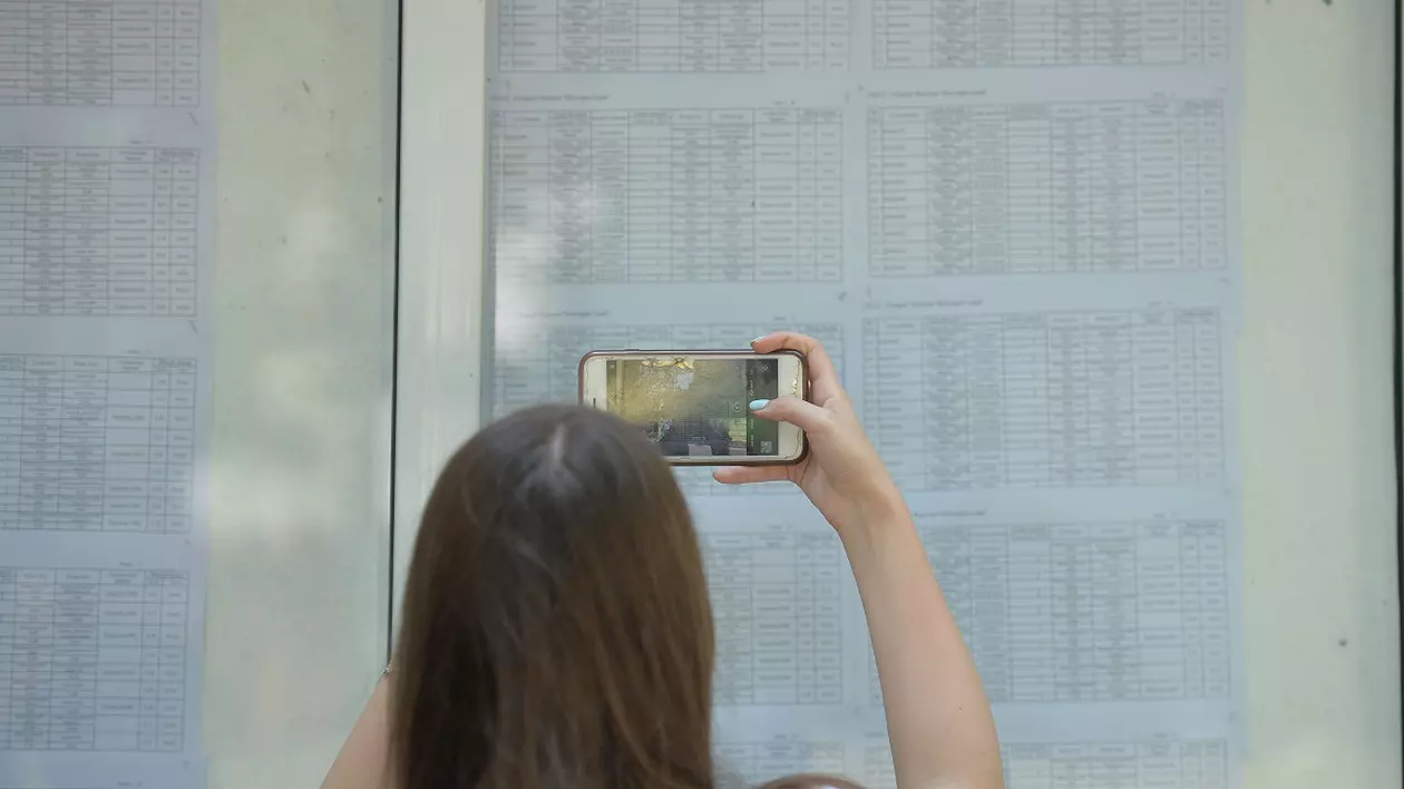 Rezultate BAC Iaşi 2025. Notele, publicate pe edu.ro - Imagine cu o elevă care fotografiază rezultatele la bac afişate la avizier