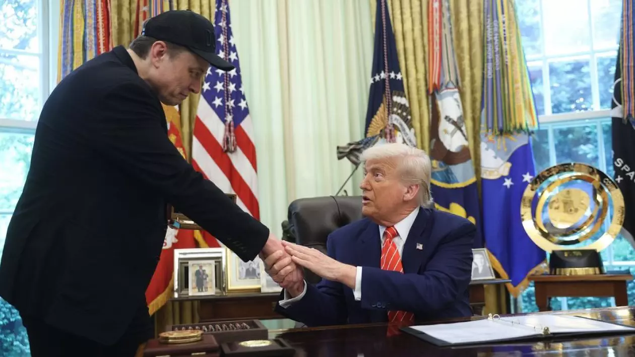 Elon Musk, imbracat în negru, sta în picioare, si da mana cu Donald Trump, care sta pe scaun în Biroul Oval