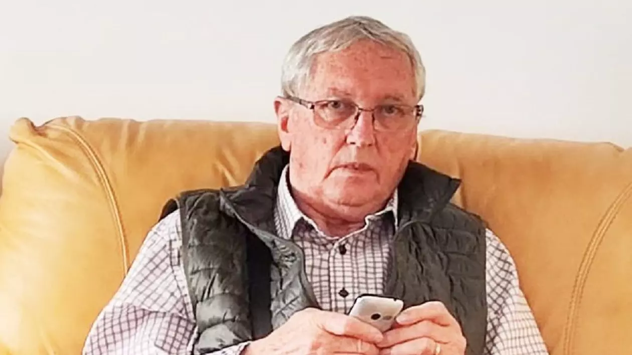 Emeric Dembrovschi stă pe o canapea, în mână ține un telefon mobil