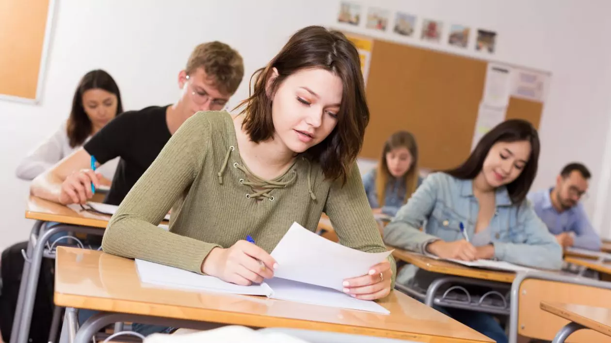 Elevi care stau în bănci câte unul și dau un examen