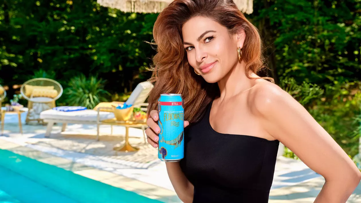 Eva Mendes la psicina intr-un costul de baie intreg negru decupat pe un umar, tine in mana o doza albastru turqoise de Floe Water