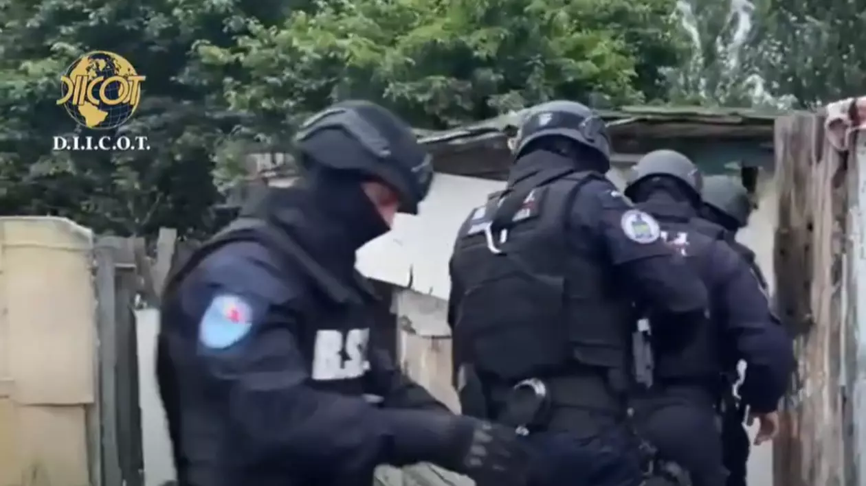 Imaginea surprinde momentul în care o echipă de intervenție a poliției, echipată cu veste antiglonț și căști de protecție, desfășoară o percheziție.
