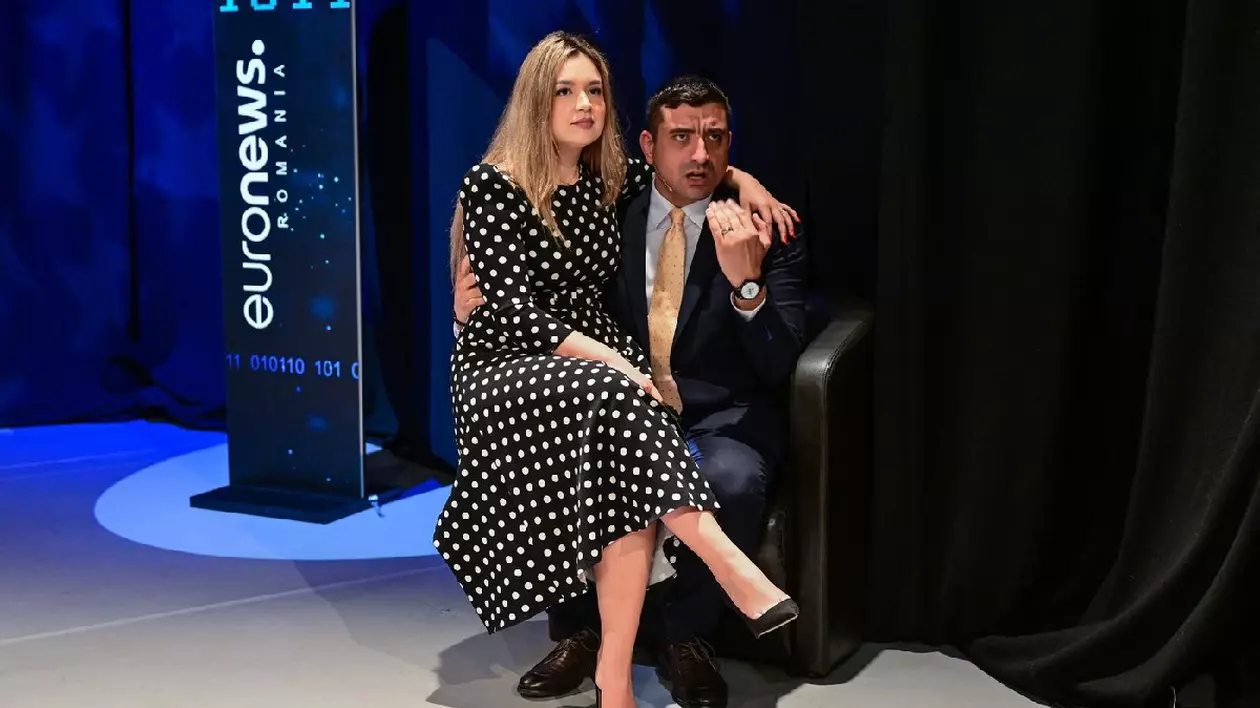 George Simion și soția sa Ilinca în timpul unei dezbateri împotriva adversaruluiNicușor Dan (nu apare în fotografie) organizată de Euronews România la București, 8 mai 2025. Ilinca, îmbrăcată într-o rochie neagră cu buline albe, stă ăn brațele lui George Simion, care este îmbrăcat într-un costum închis la culoare, cămașă albă și cravată aurie, și gesticulează.