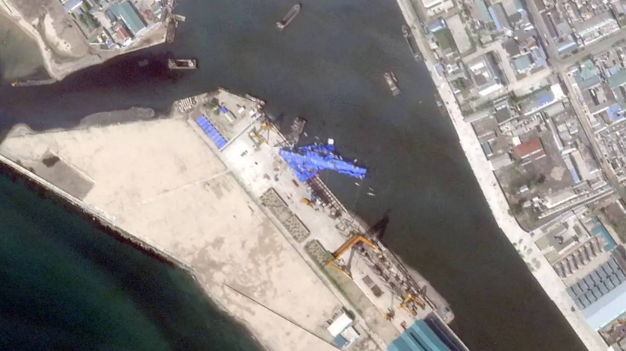 Această imagine din satelit, realizată și publicată pe 23 mai 2025 de Planet Labs PBC, arată o nouă navă de război nord-coreeană care pare să se fi răsturnat în port după ceremonia de lansare din Chongjin.