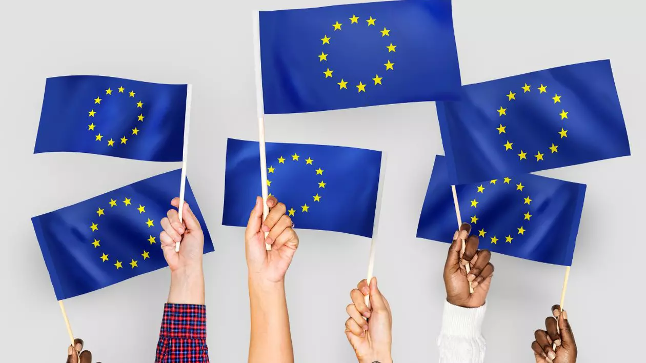 persoane care țin în mână stegulețe cu drapelul Uniunii Europene