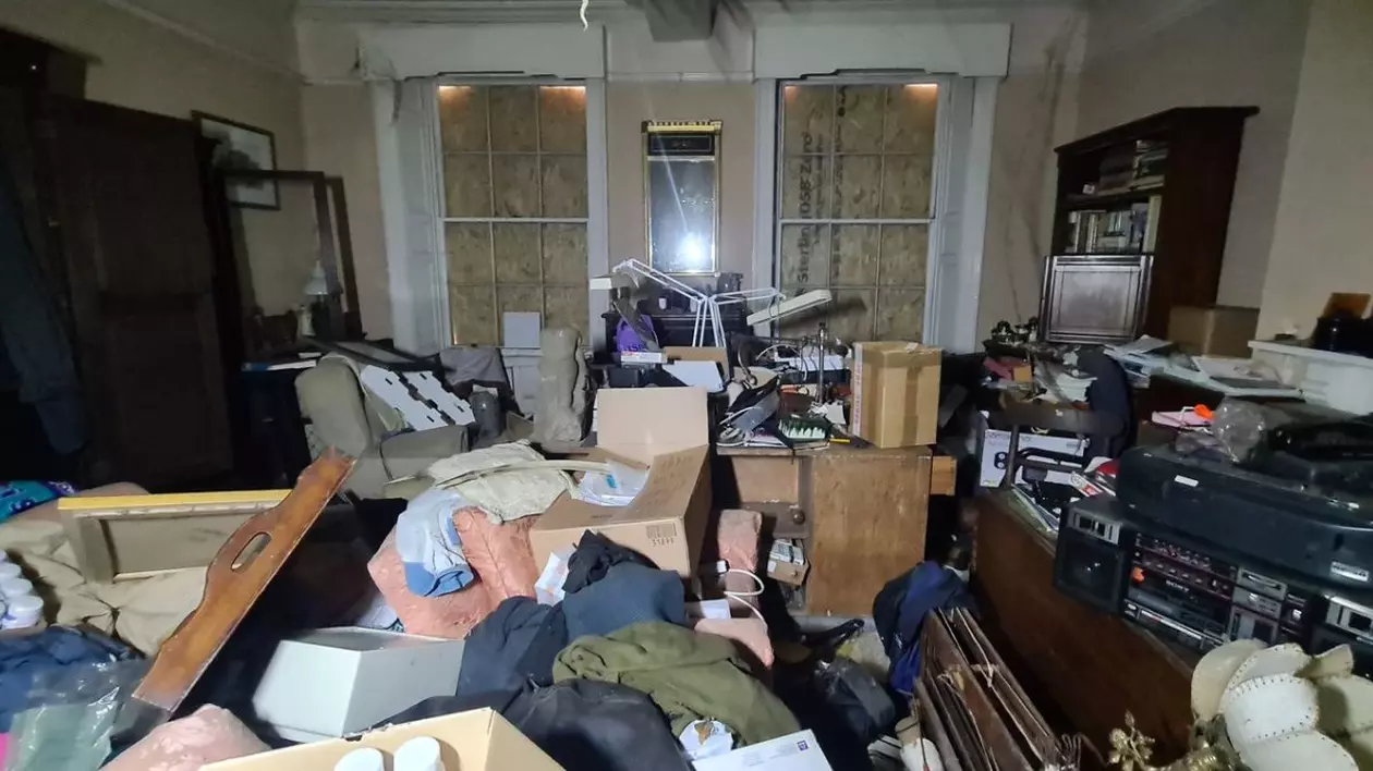 interiorul unei case vechi de sute de ani, cu multe cutii si bunuri aruncate, acoperite de praf
