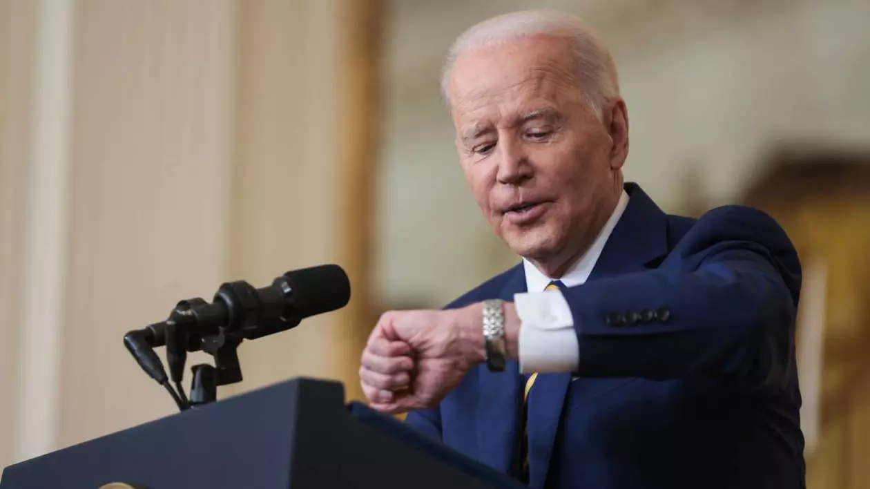 Fostul președinte american Joe Biden, în timpul unor declarații de presă, este îmbrăcat la costum și se uită la ceas.