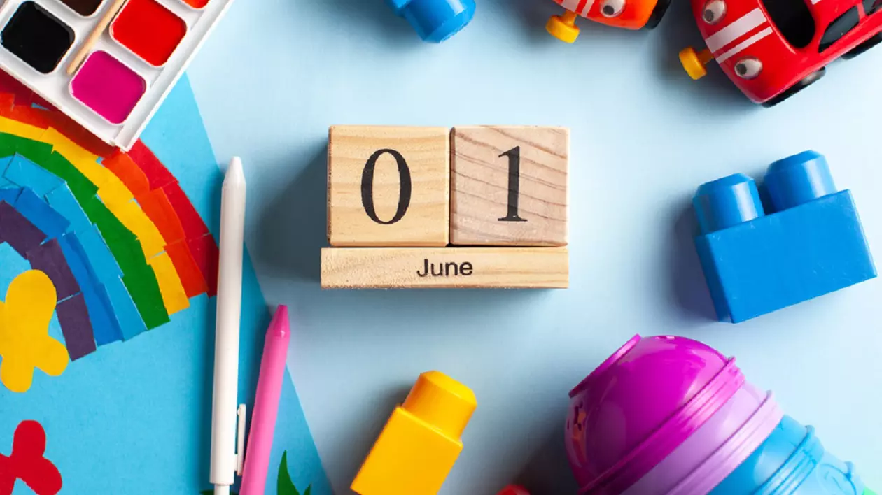 Mesaje de 1 Iunie – urări de Ziua Copilului - Imagine cu jucări care înconjoară trei piese de lemn aranjate ca să arate mesajul 1 June