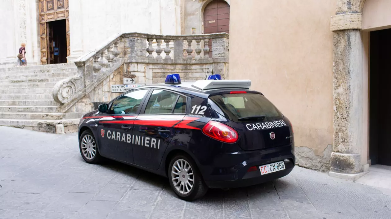 În imagine este ilustrată o mașină de carabinieri, în fața unei locuințe