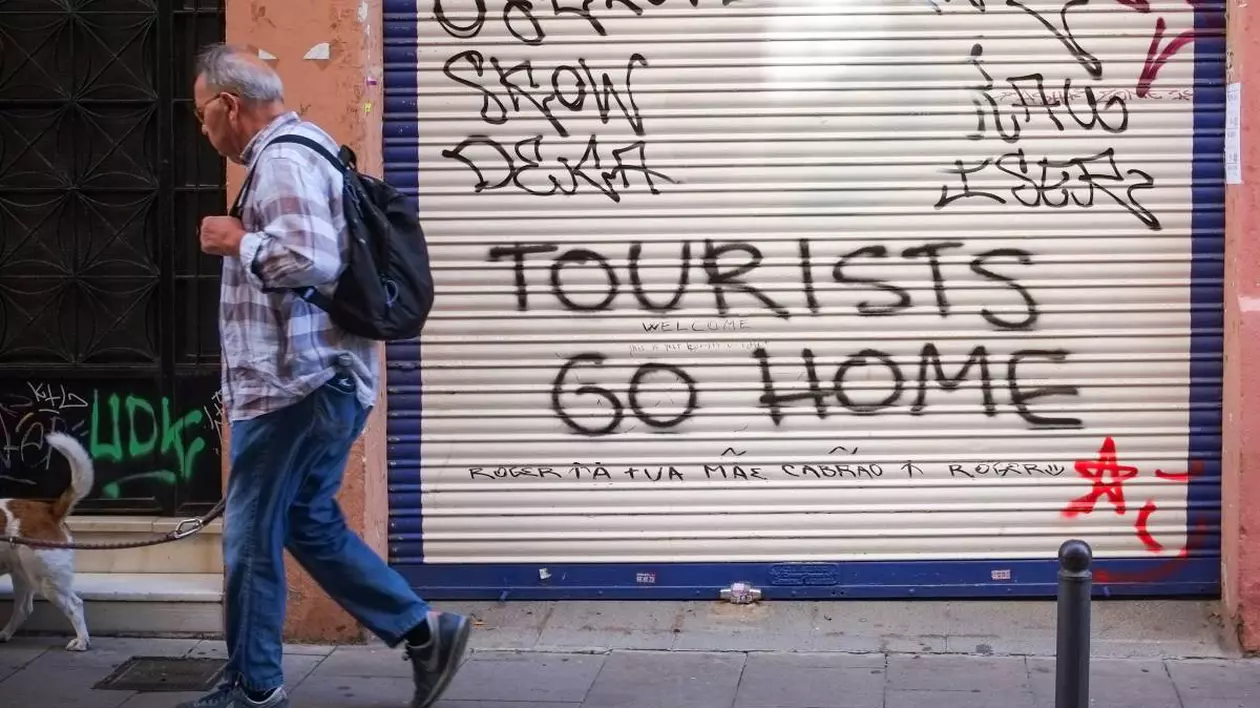 Mesajul „turiști, plecați acasă” este scris pe peretele unei clădiri din Spania.
