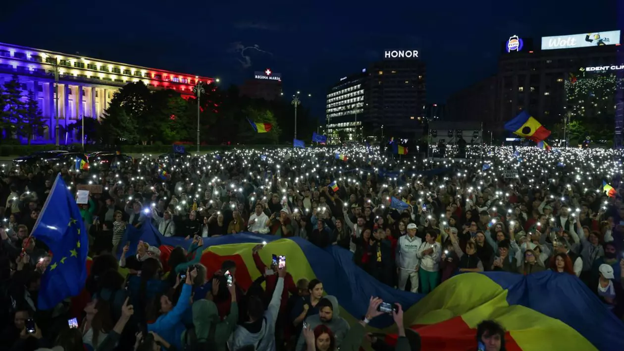Oameni prezenți la mitingul „România în Lumină” cu telefoanele aprinse, la lăsarea întunericului.