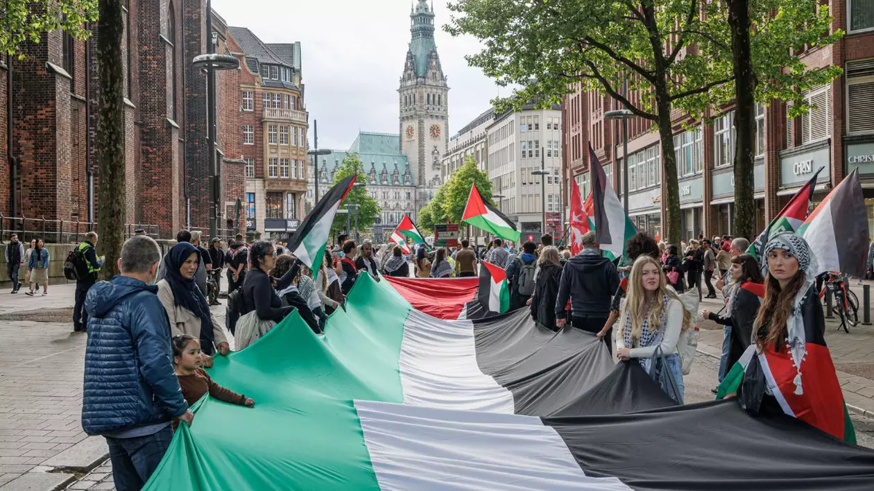 Oameni țin un steag palestinian mare în timpul unui miting pro Palestina în Hamburg.