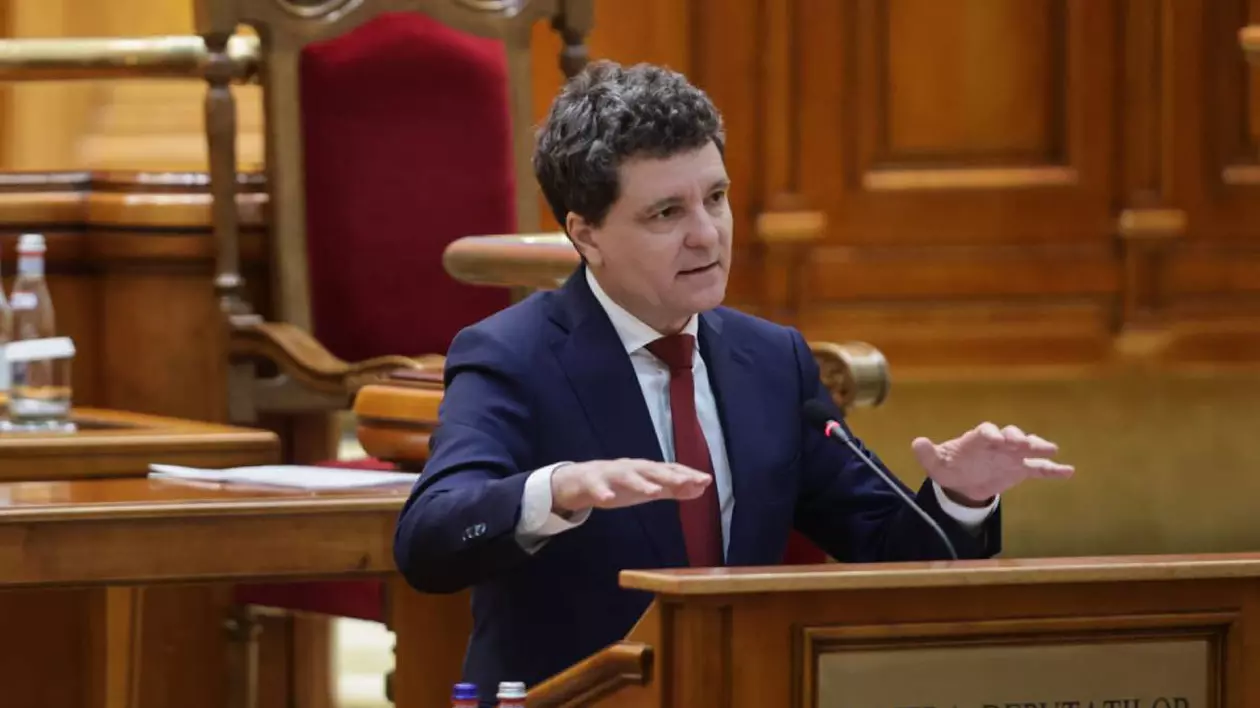 Nicușor Dan, în timpul primului discurs în Parlamentul României, acesta stă la pupitrul de la Camera Deputaților și este îmbrăcat la costum, are o cravată roșie.