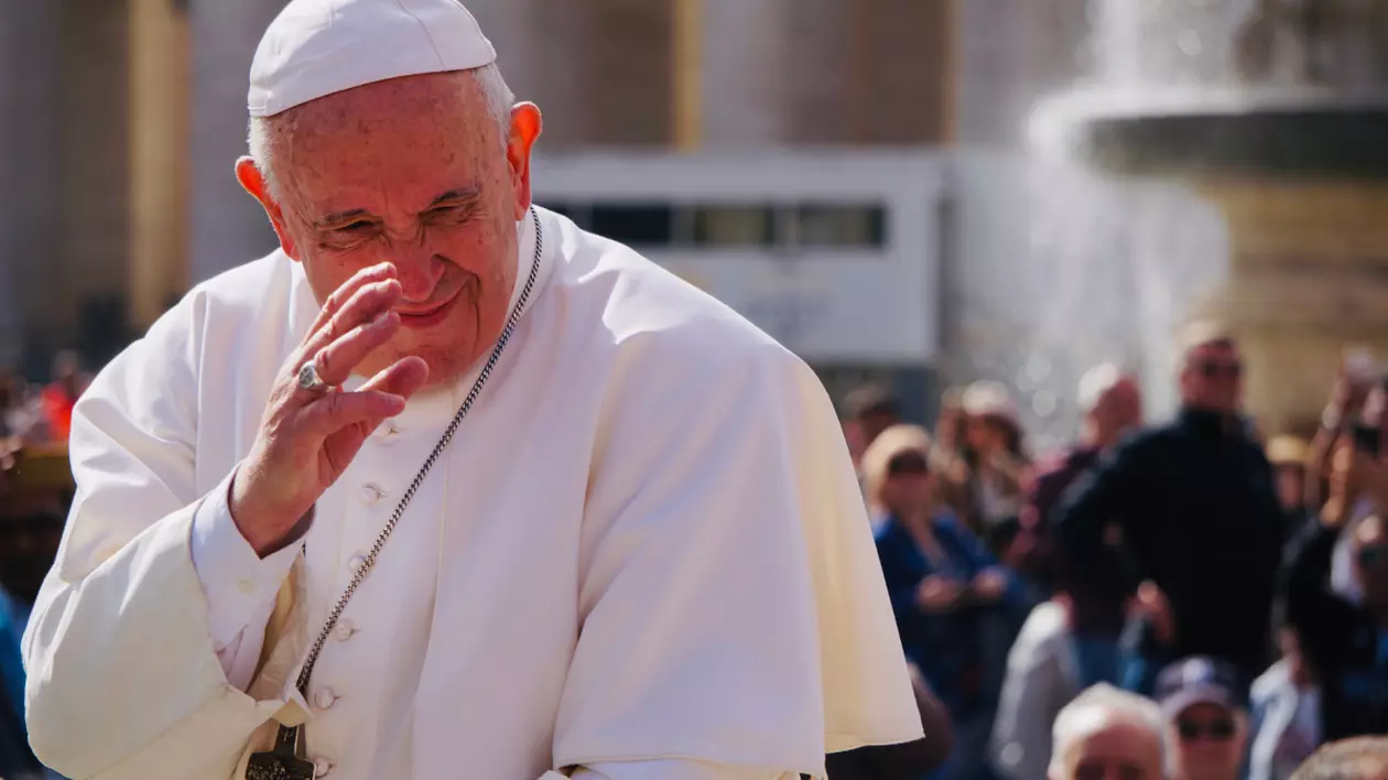 Papa Francisc, la Vatican, salutând mulțimea de oameni. Este îmbrăcat în haine specifice, albe, și are o cruce la gât.