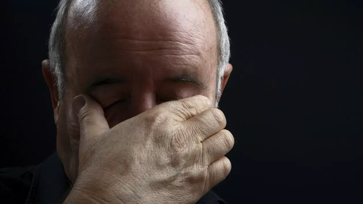 Imagine creativă cu un pensionar, cu chelie, care ține mâna la ochi, pe fundal negru