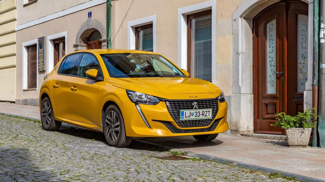 Poză cu un Peugeot 208 galben parcat în fața unei clădiri
