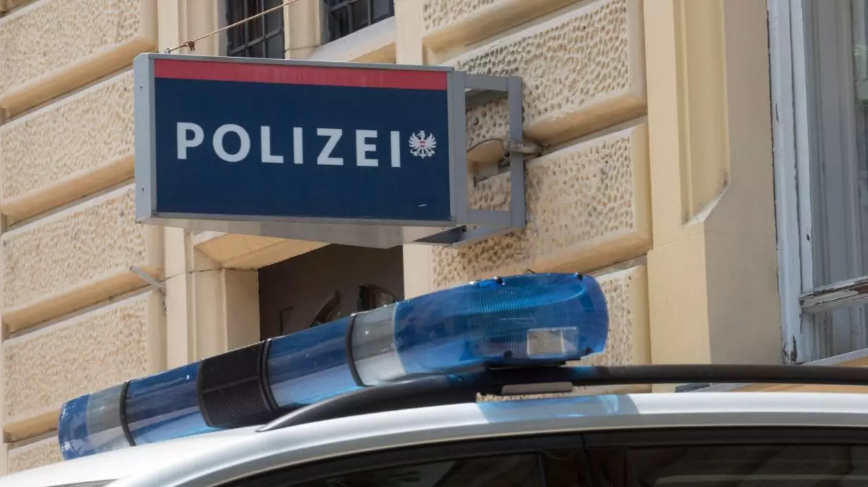 Sigla Poliției din Austria se vede pe peretele instituției, iar sub ea este o mașină a polițiștilor, cu girofar