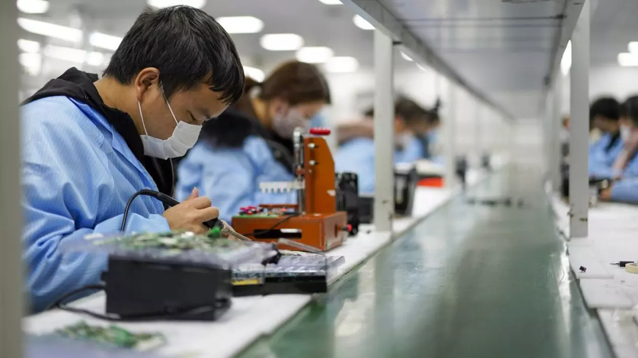 Angajații lucrează în atelierul unei companii de electronice din Chongqing, China