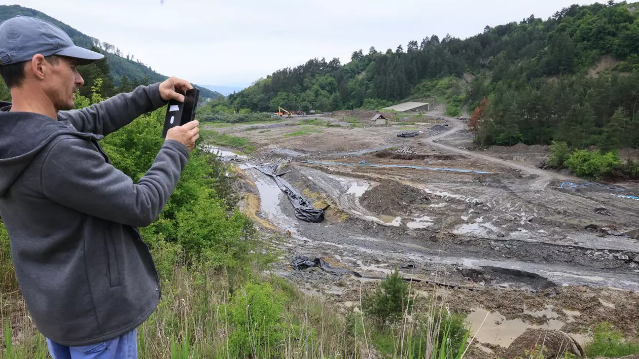 imagine cu un barbat care fotografiaza apă intr-o zona cu namol, inconjurata de padure