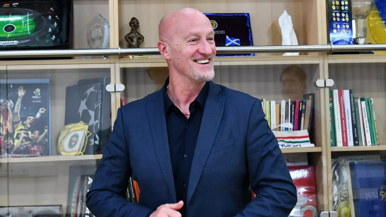 Marco Rosii zâmbește, pe fundal e o bibliotecă albă
