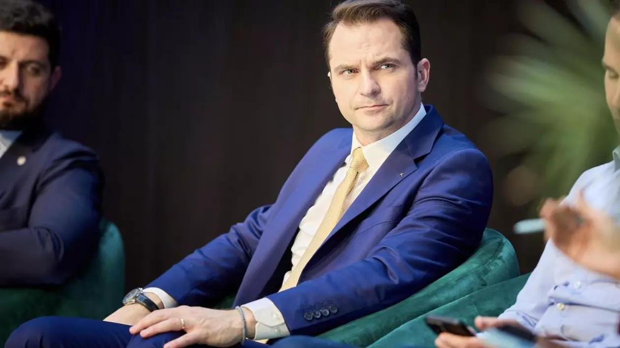Ministrul Energiei, Sebastian Burduja, stă pe scaun, fiind invitat la un eveniment din energie
